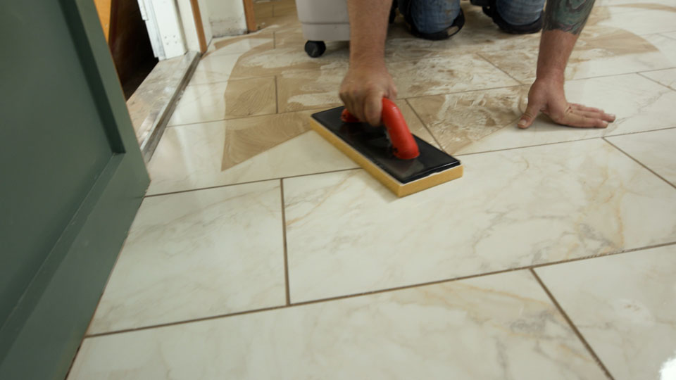 man using the Ultra Grouting System sponge to wipe away remaining grout haze